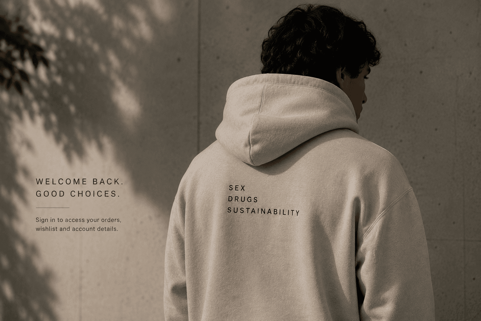 Model wearing stone SDS hoodie against concrete wall.